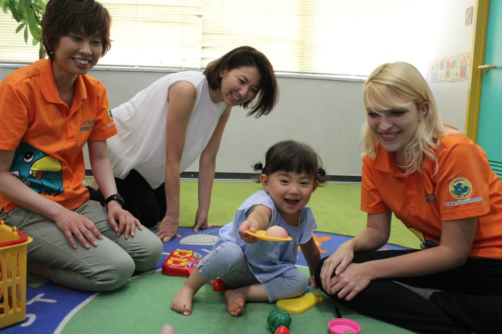 親子と先生が教室でおもちゃを使って楽しむ様子