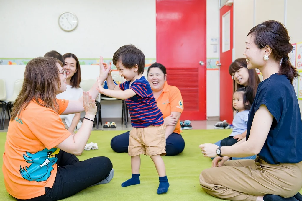 先生と子どもがハイタッチし、保護者が見守る様子
